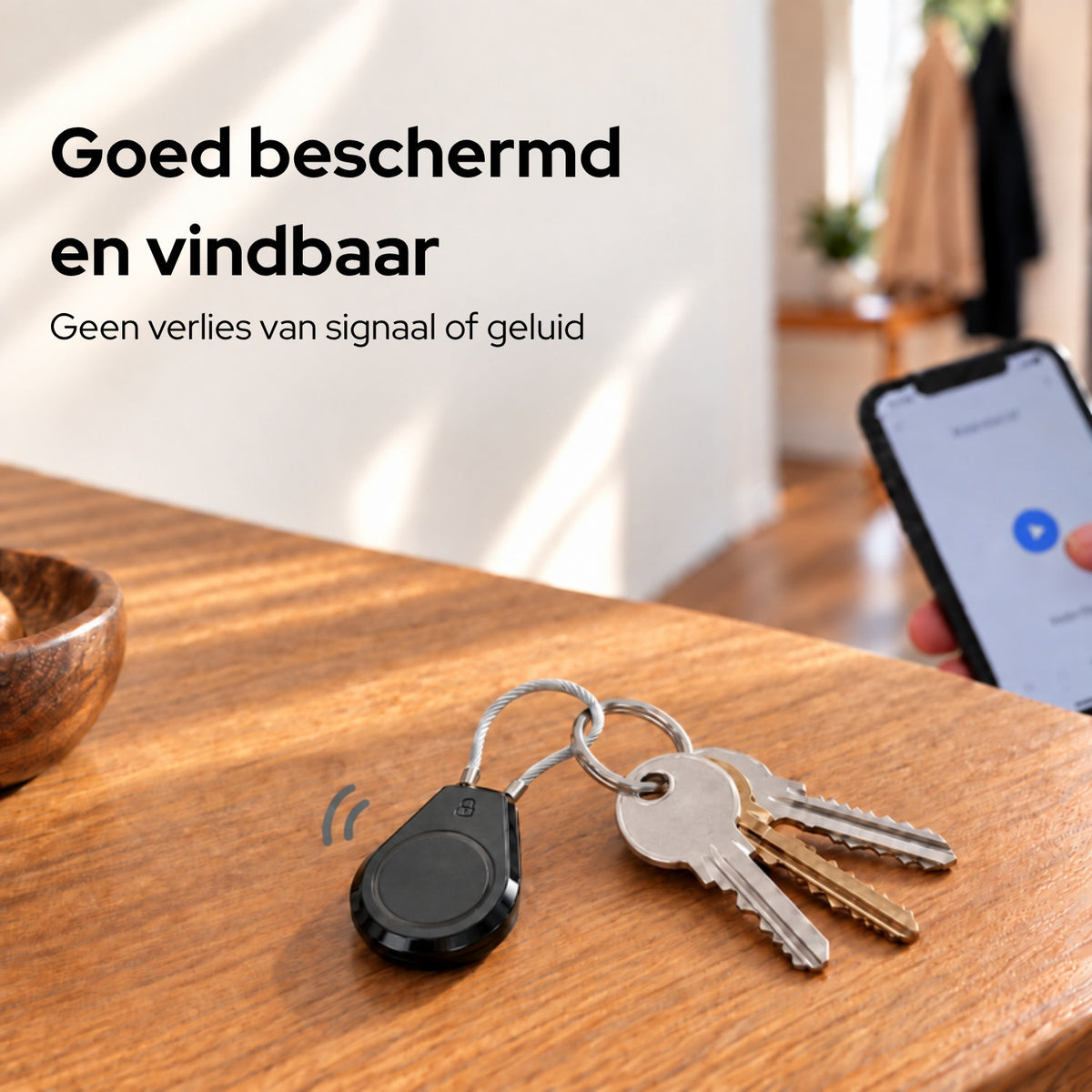 AirTag-houder aan een sleutelbos op tafel, met een telefoon op de achtergrond